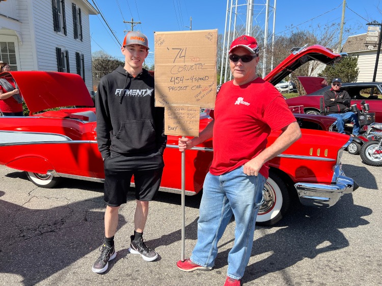 Two men with a handmade sign selling a 1974 Corvette