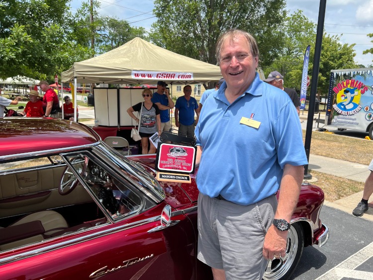 The Mayor of Loganville holding the Mayor's Choice award at a car show