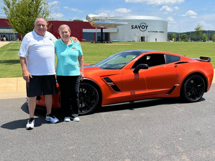 Two people with their Sebring Orange C7 Corvette at the SAVOY Museum