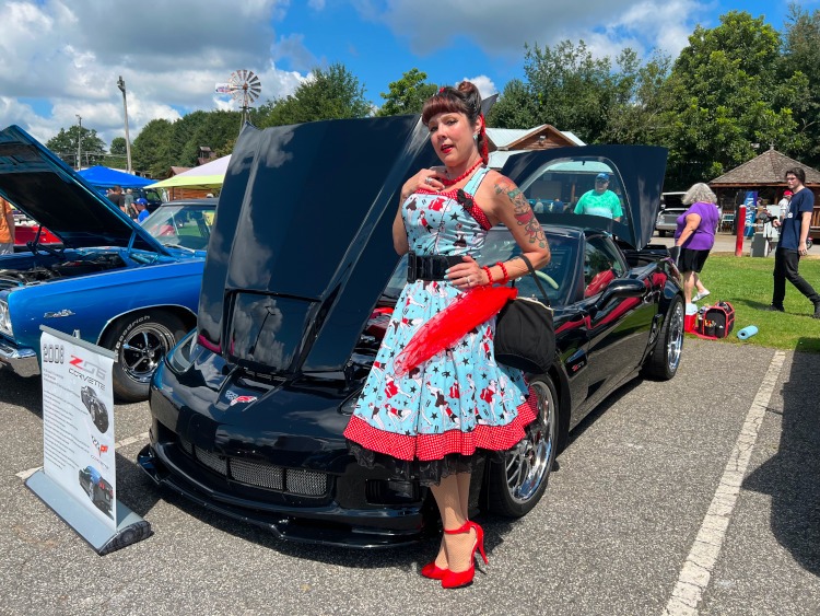 Pinup Model standing beside a Black 2008 Z06 Corvette coupe