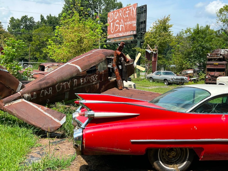 Old Car City USA sign with a propeller airplane and red car