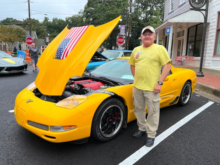 A man standing near a FRC yellow Corvette