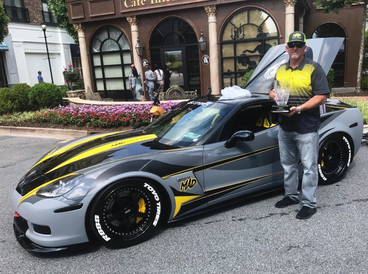 Man holding trophy beside a custom Corvette