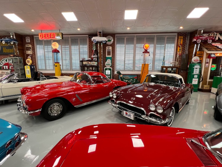 Two vintage red Corvettes inside a museum