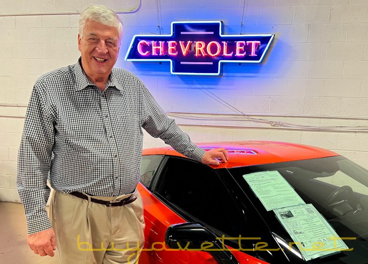 Man standing beside a seventh-generation Sebring Orange Corvette coupe.