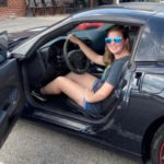 Young girl sitting in a black Corvette coupe