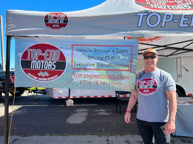 A man standing beside the Top-End Motors business logo.