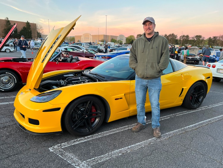 Man standing beside a yellow 2007 Z06 Corvette coupe.