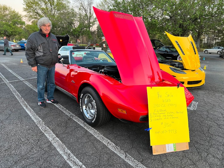 Man standing beside a red 1973 convertible Corvette.