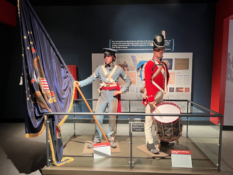 A display of 1812 soldiers uniforms and flag at the U.S. Infantry Museum.