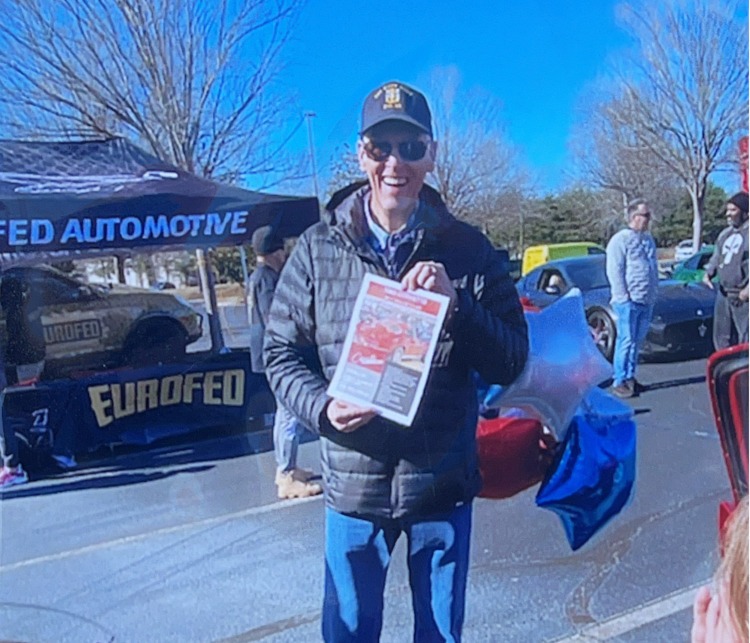A man holding a car show flyer.