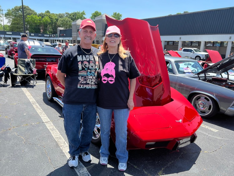 Two people are standing beside a C3 1979 custom Corvette coupe.