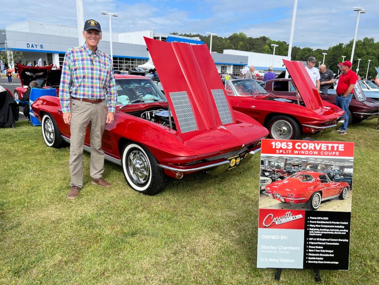 A man at a car show with a red Corvette.