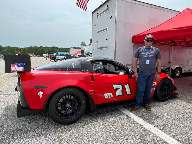 A man standing beside his #71 Corvette race car.