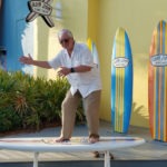 A senior citizen on a stationary surfboard.