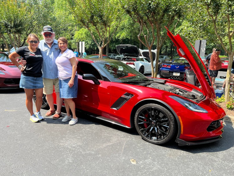 Three people standing beside a seventh-generation 2016 Z06 Corvette coupe