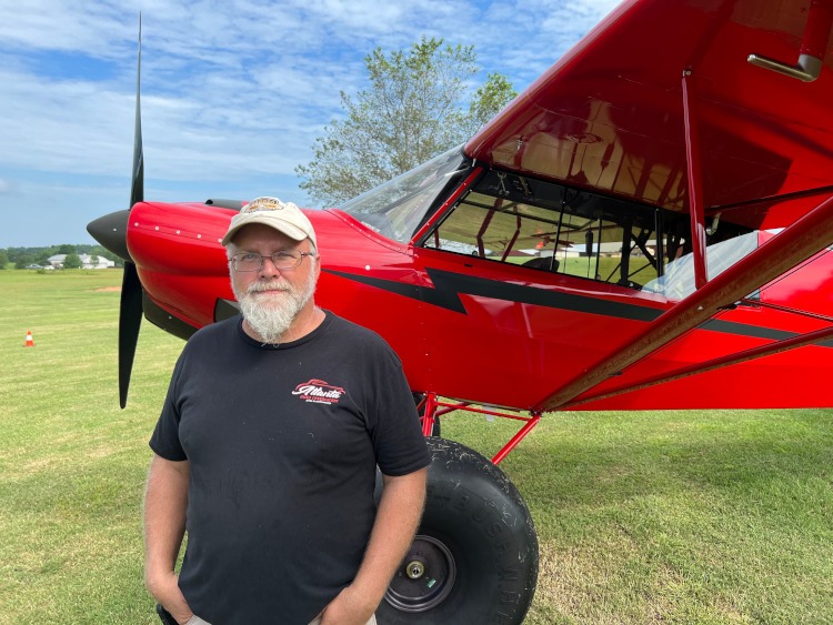 man standing beside a red prop kit airplane