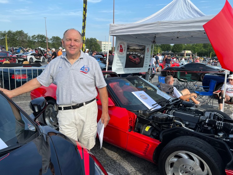 A man standing beside a red Corvette