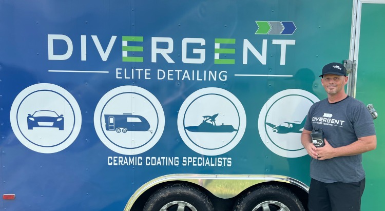 A man is standing beside a Divergent Elite Detailing trailer.