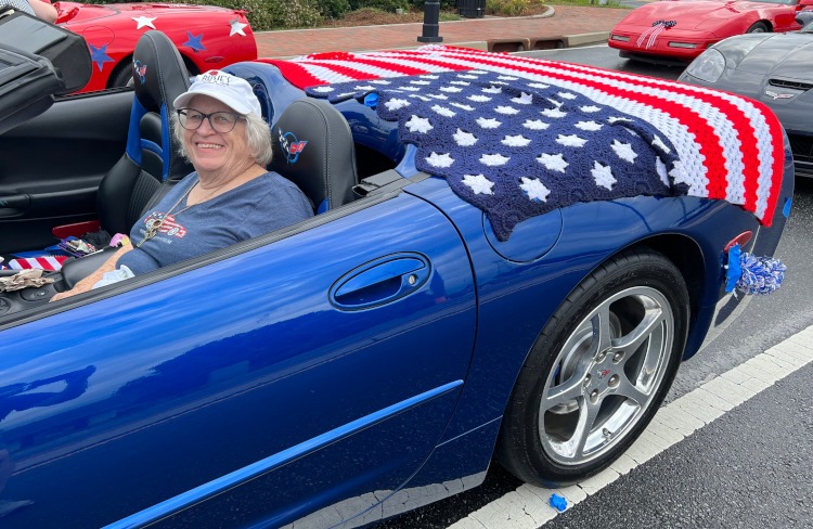 A woman is sitting in a blue C5 Corvette convertible