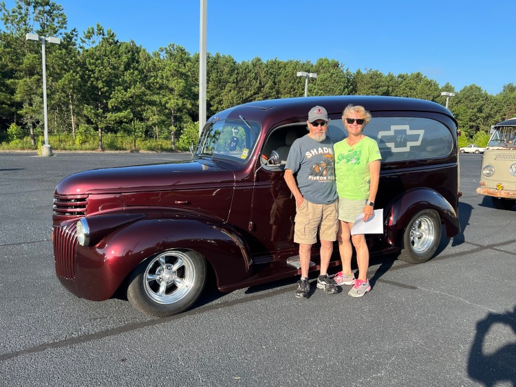 Two people are standing beside a custom 1941 Chevrolet Panel truck.