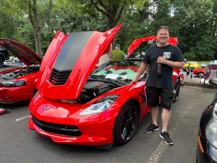 C7 Torch Red Corvette coupe at a car show.