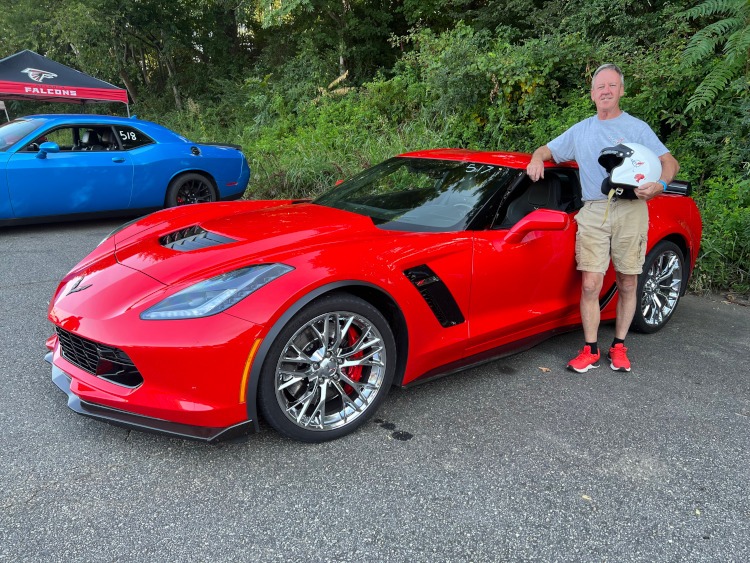 A man standing beside a torch red Corvette