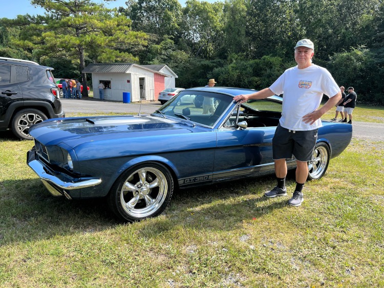 A blue 1966 fastback Mustang coupe at a car show.
