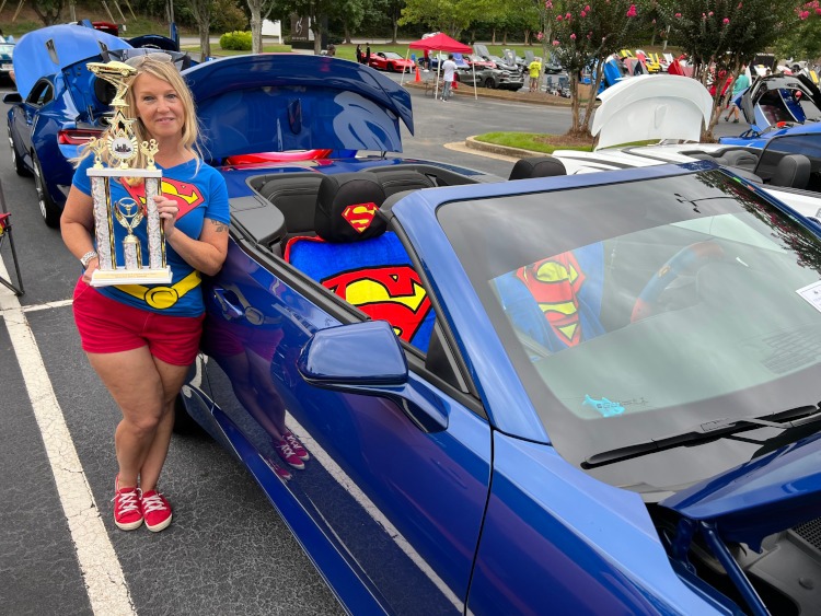 A blue 2022 Camaro with a woman holding a trophy.