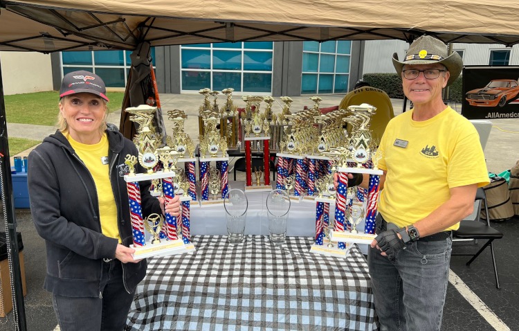 Two car club members holding trophies.