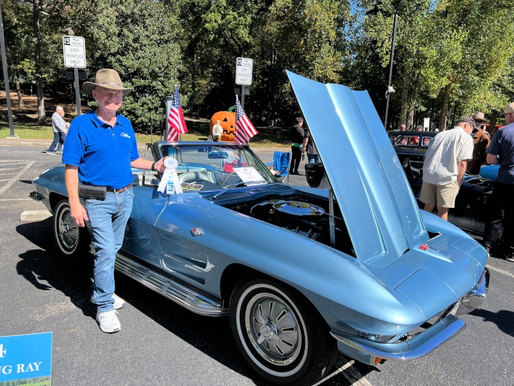 A blue convertible Corvette with side pipes