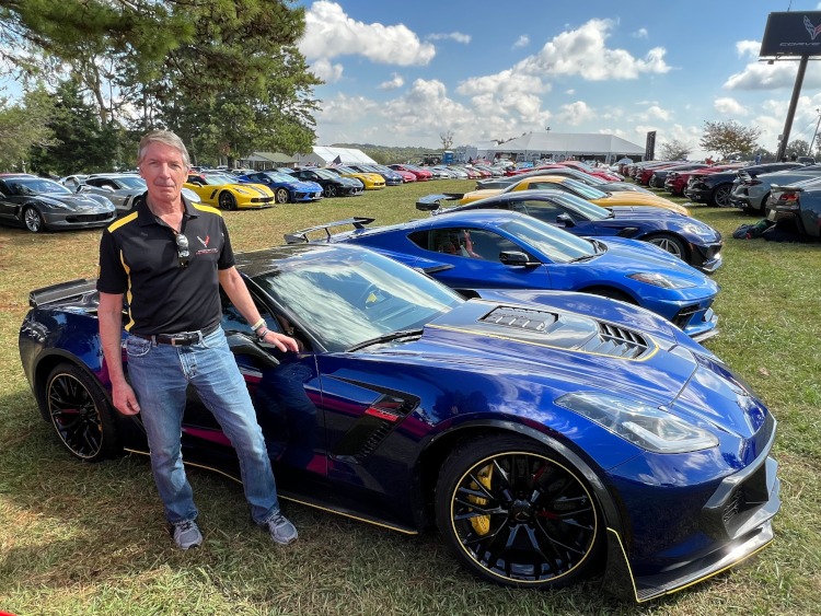A man standing beside a blue seventh-generation Corvette.