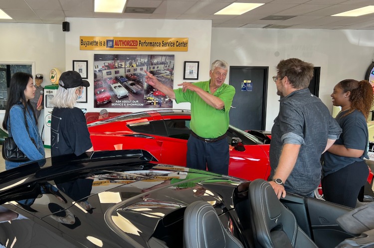 A group of people standing in a Corvette car show room.