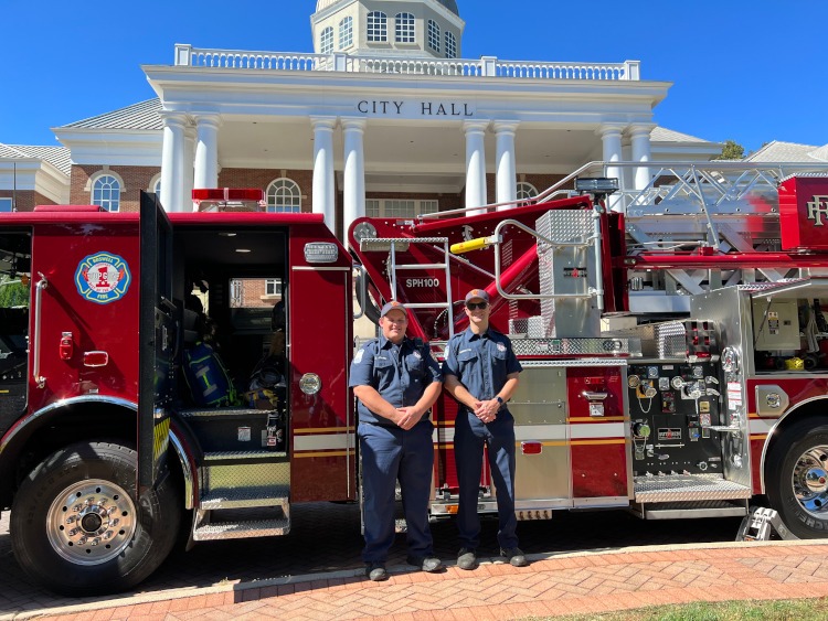 Two members of the Roswell fire department standing beside truck #21.