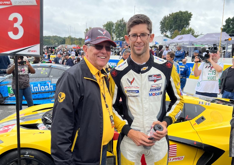 Two men are standing beside a 2023 C8.R racecar.