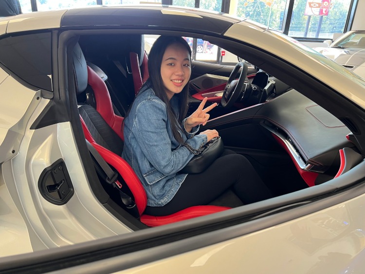 A woman sitting inside an eighth-generation Corvette coupe.