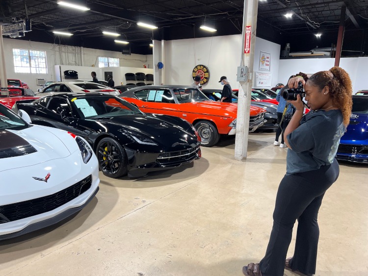 A college student taking a photo of a C7 Corvette.