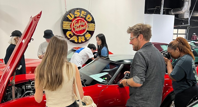 People standing around a third-generation Corvette.
