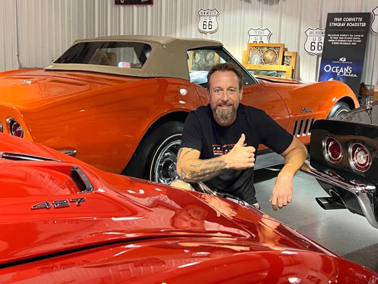A man is beside three classic Corvettes