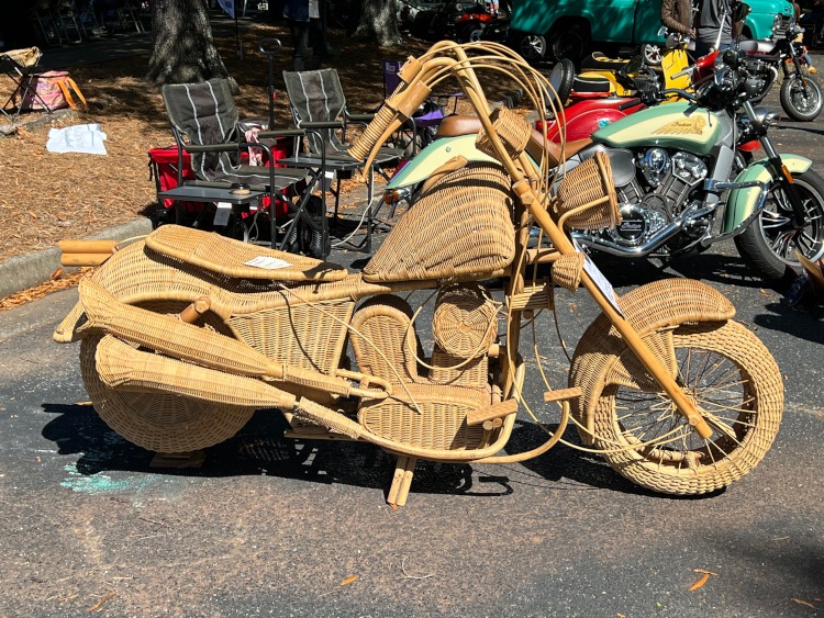 A motorcycle made out of brown wicker at a car show.