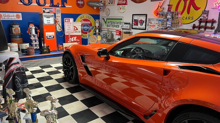 An orange C7 Corvette in a custom garage