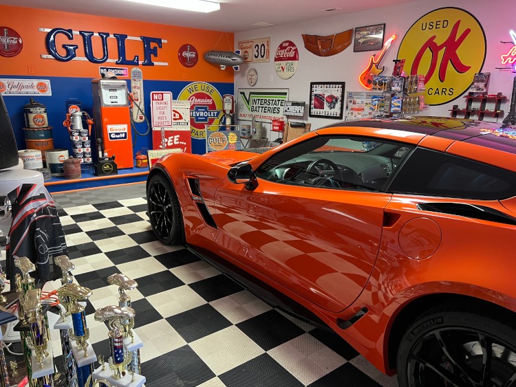 An orange C7 Corvette in a custom garage
