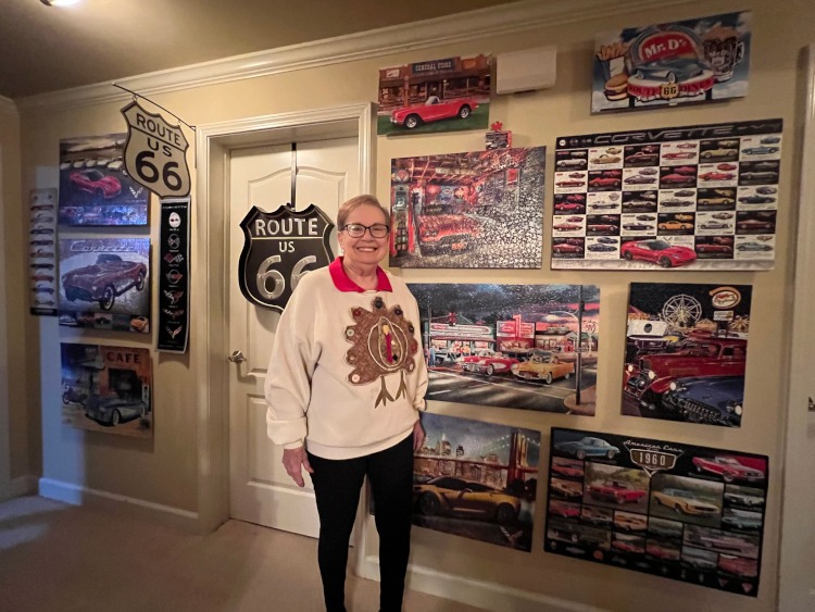A woman standing beside a wall of Corvette puzzles.