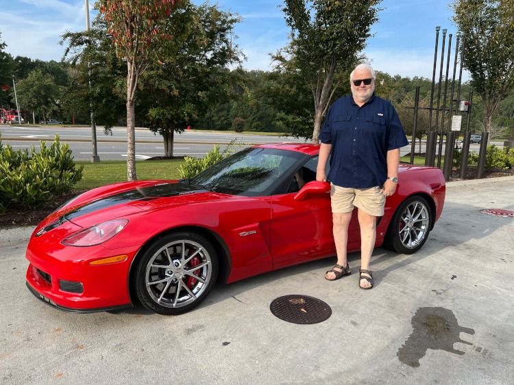 A man is standing beside a red Z06 Corvette coupe. Sixth-generation.