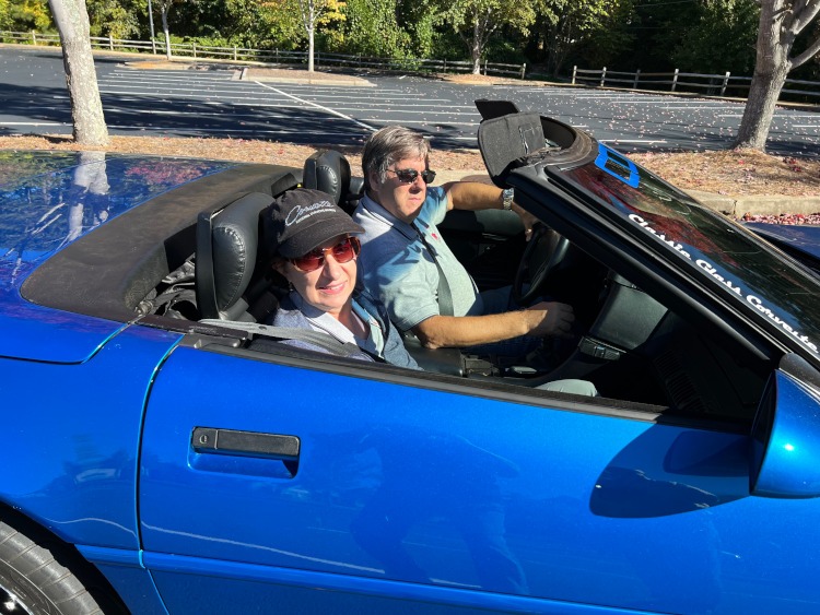Two people are sitting in a fourth-generation 1992 blue Corvette.