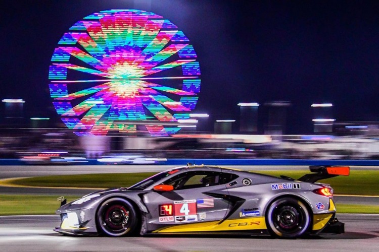 A gray C8 racecar with a Ferris Wheel in the background.