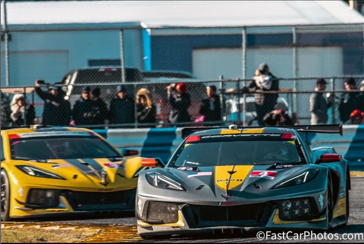 Two C8.R factory race Corvettes going around a corner.