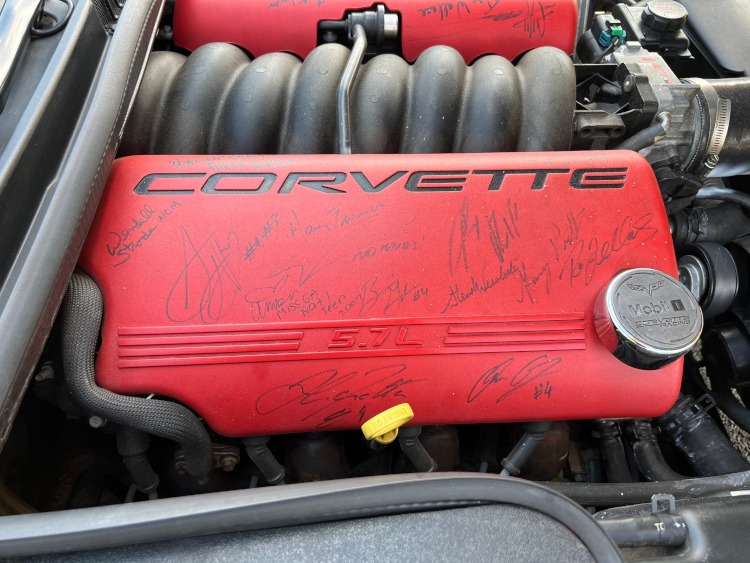 Various signatures on red Corvette fuel rail covers.