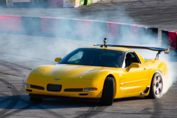 A yellowCorvette is drifting around a track.