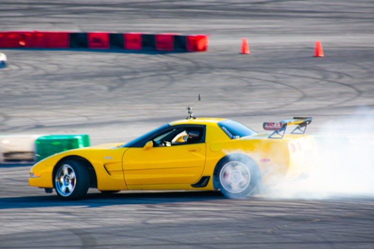 A yellow Corvette drifting around a track.